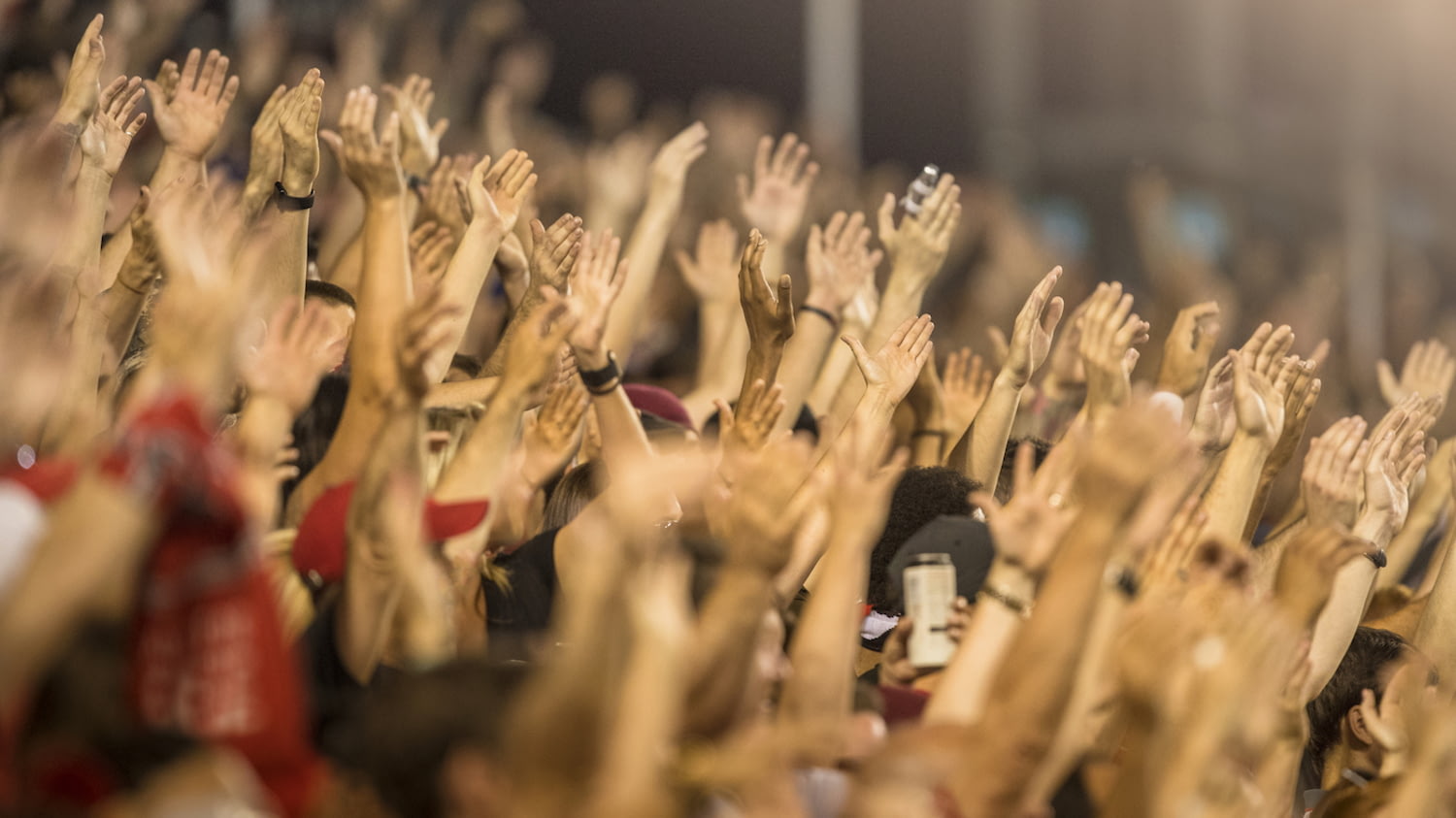 Dutzende Menschen im Fanblock recken gemeinsam die Hände in die Höhe