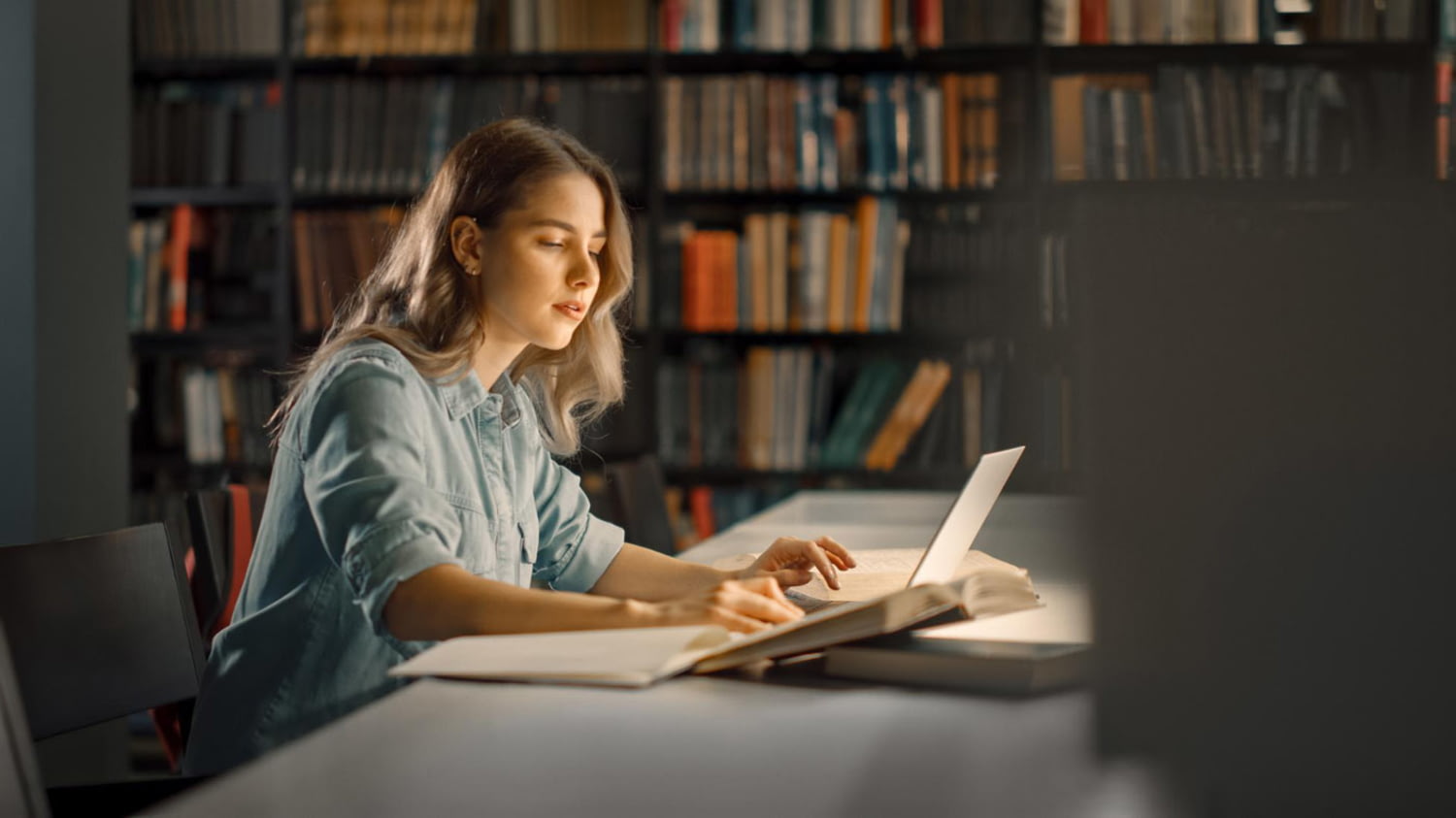 Junge Frau in der Bibliothek arbeitet an ihren Laptop