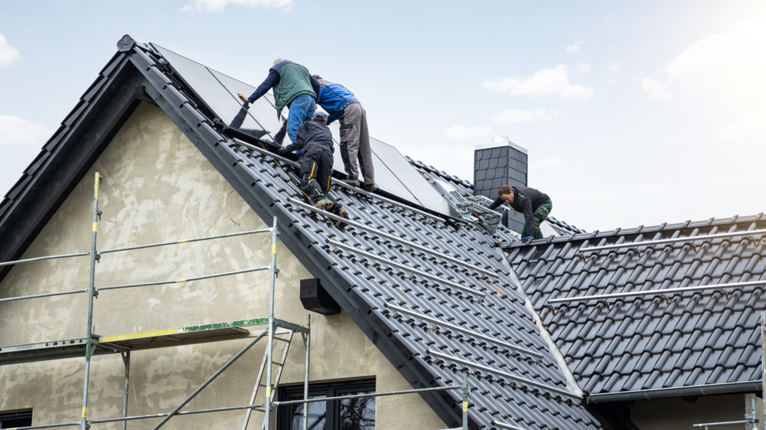 Facharbeiter installieren eine Photovoltaikanlage auf einem neuen Einfamilienhaus