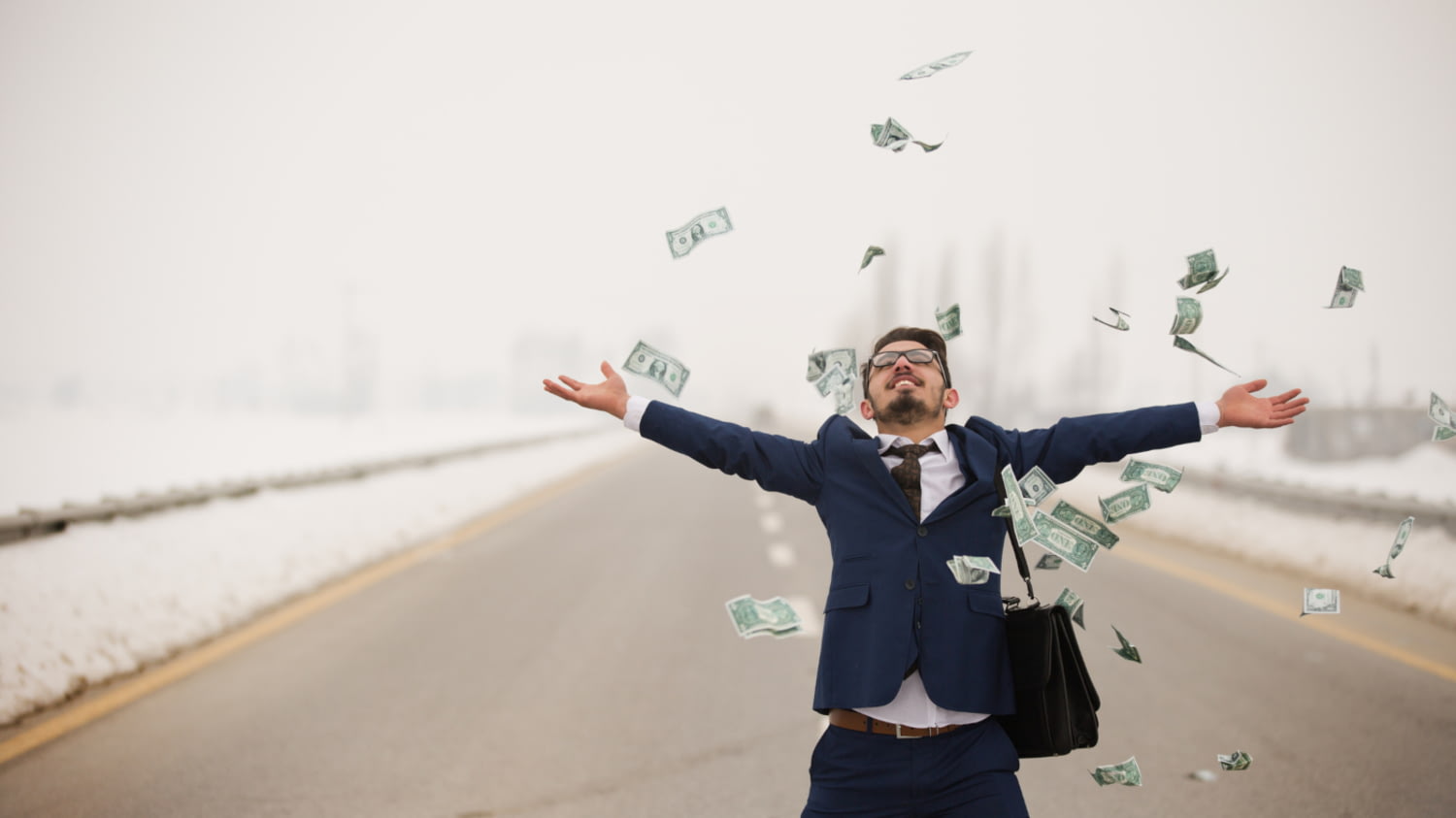Geschäftsmann wirft auf einer unbefahrenen Straße mit Geldscheinen um sich