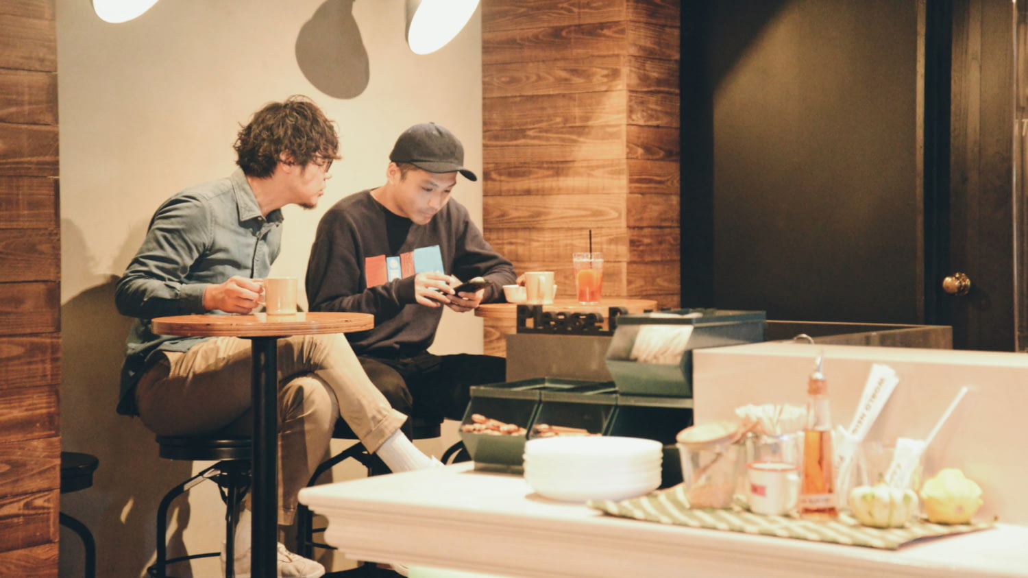Zwei junge Männer sitzen in einer Arbeitspause am Cafétisch zusammen