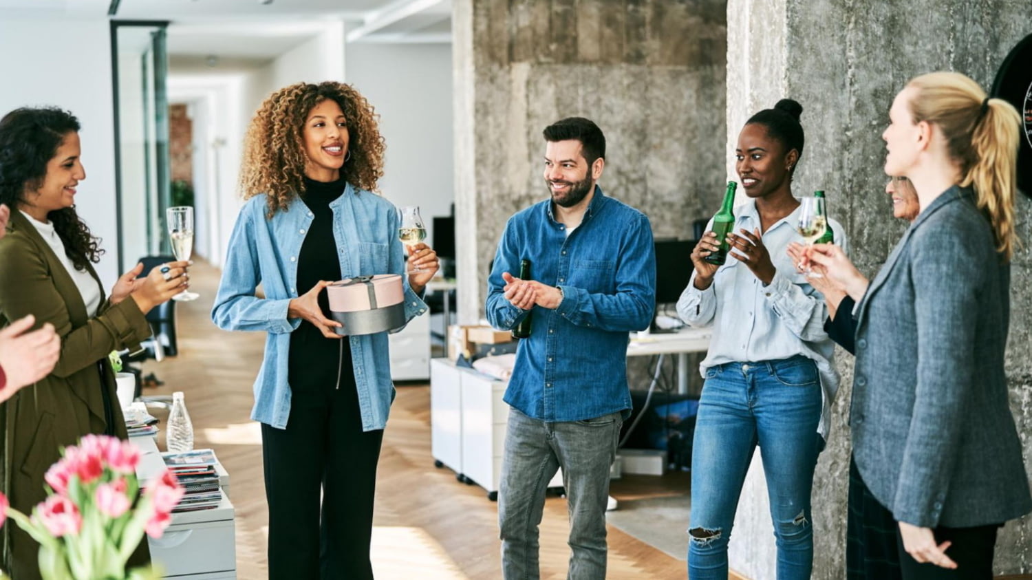 Arbeitskolleg*innen überreichen einer Kollegin ein Geschenk