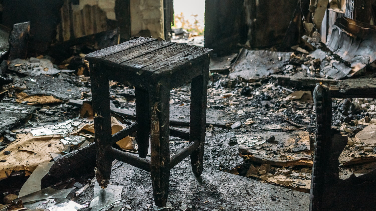Hausratversicherung: Ein ausgebranntes Zimmer mit einem verkohlten Holzschemel im Mittelpunkt