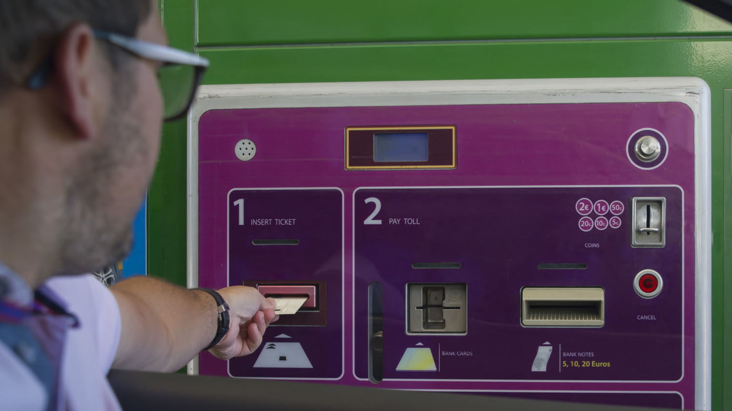 Mann bezahlt die fällige Gebühr an einer Mautstation mit einer Kreditkarte am Automaten